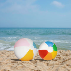 Two colorful beach balls on a sandy beach with ocean in the background