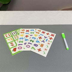 Colorful sticker sheets with numbers and symbols on a gray surface with a green marker.