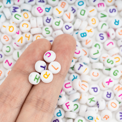 Colorful letter beads on a hand with more beads in the background