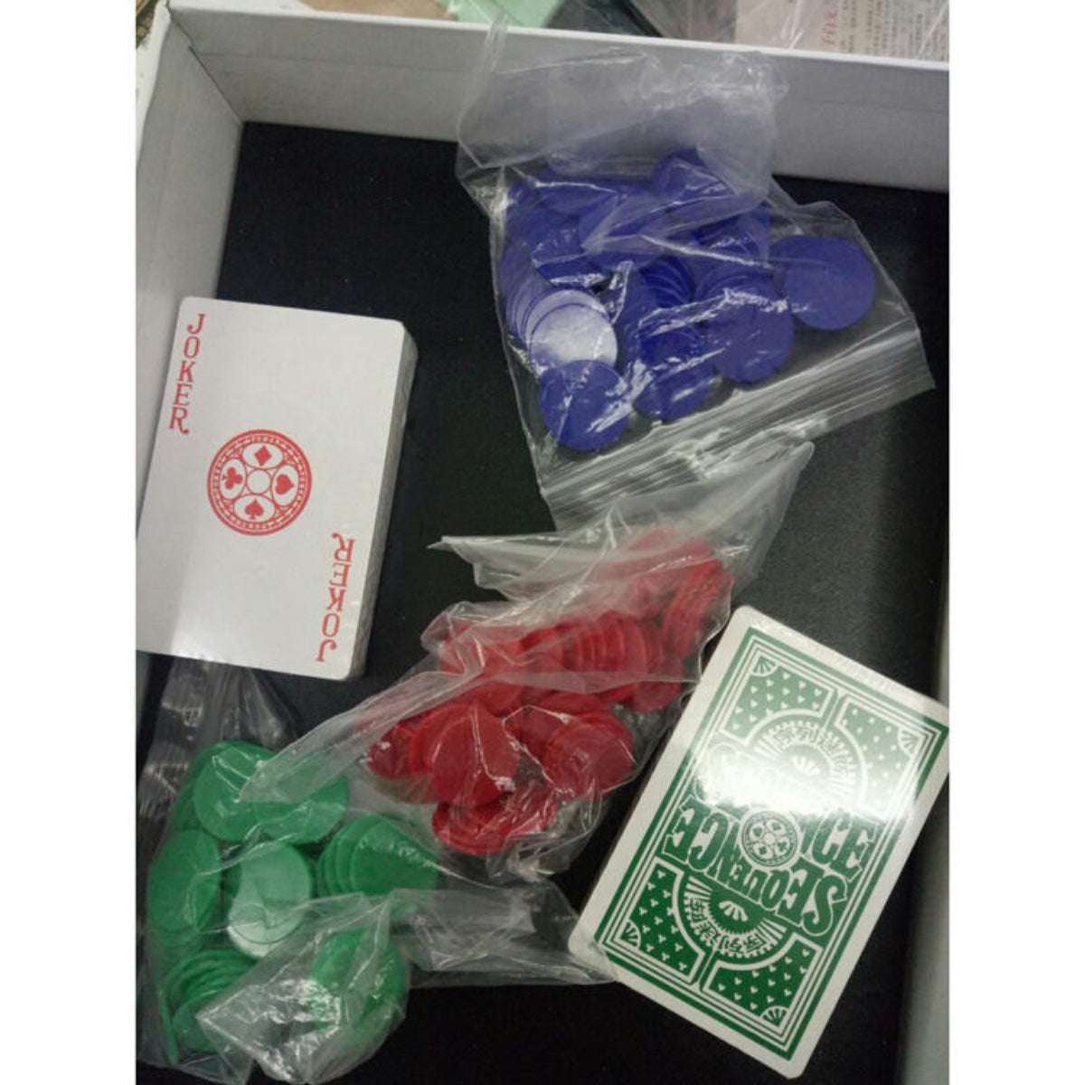 Poker cards and chips in clear bags on a black surface