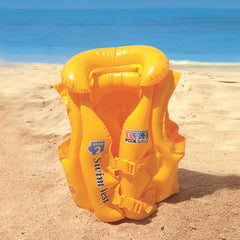 Yellow inflatable life jacket on a sandy beach with ocean in the background