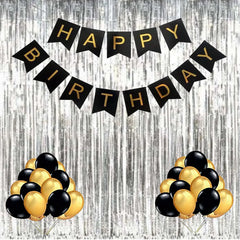 Black and gold birthday decoration set with HAPPY BIRTHDAY banner and balloon bunches on silver fringe backdrop